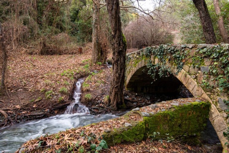 Beautiful medieval stoned bridge of Milia with river full with water flowing at Troodos mountains in Cyprus