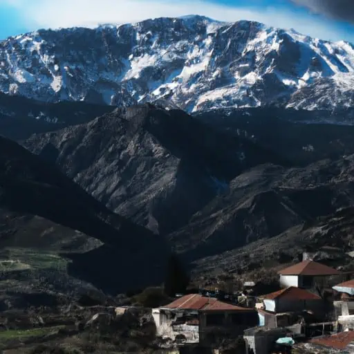 תמונה של הרים מושלגים עם כפר קפריסאי מסורתי בחזית.